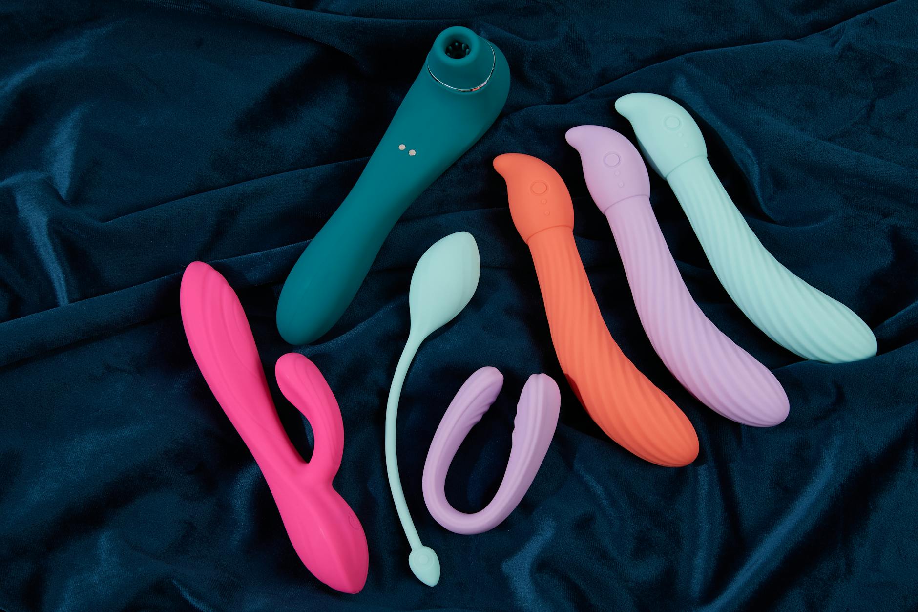 Close-up of a hand holding an orange vibrator against a purple backdrop, showcasing modern sensuality and intimate wellness