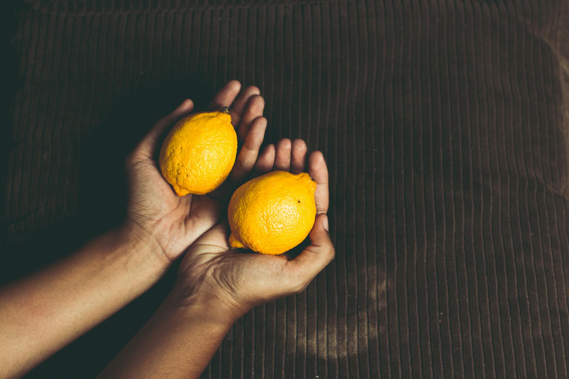 Two fresh lemons held in cupped hands, symbolizing discovery and gentle introduction