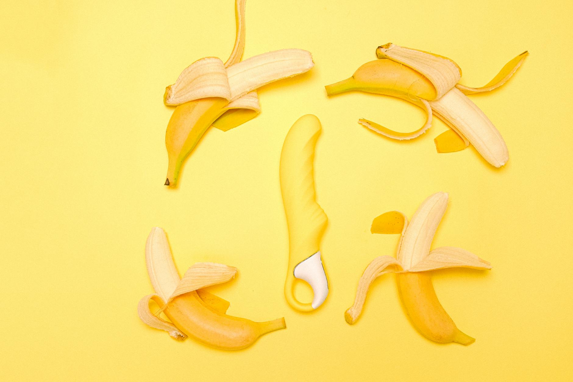Yellow silicone lemon vibrator displayed with fresh lemons on a bright yellow background