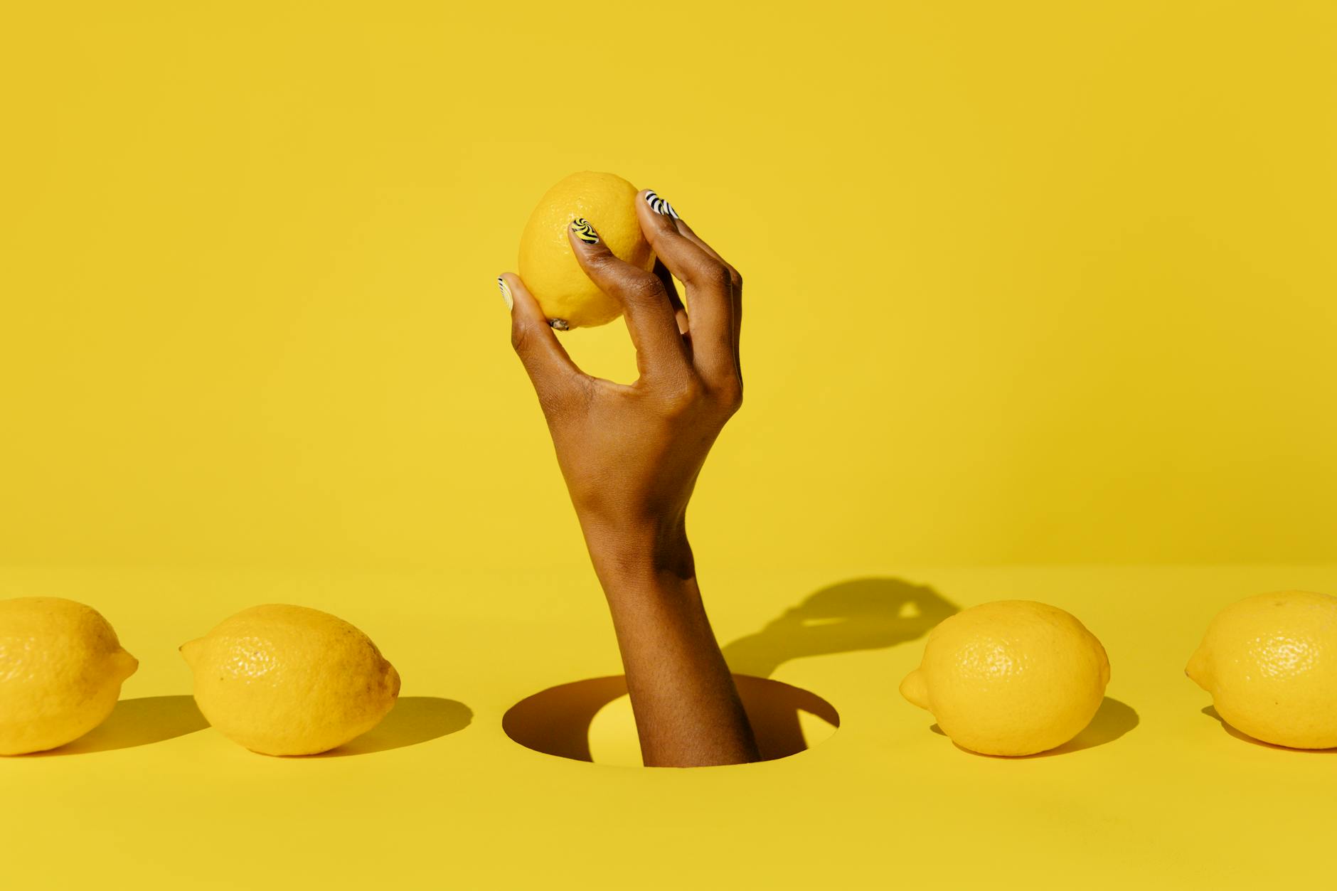 Hand holding a lemon against a vibrant yellow background, symbolizing the fresh intensity of lemon vibrators