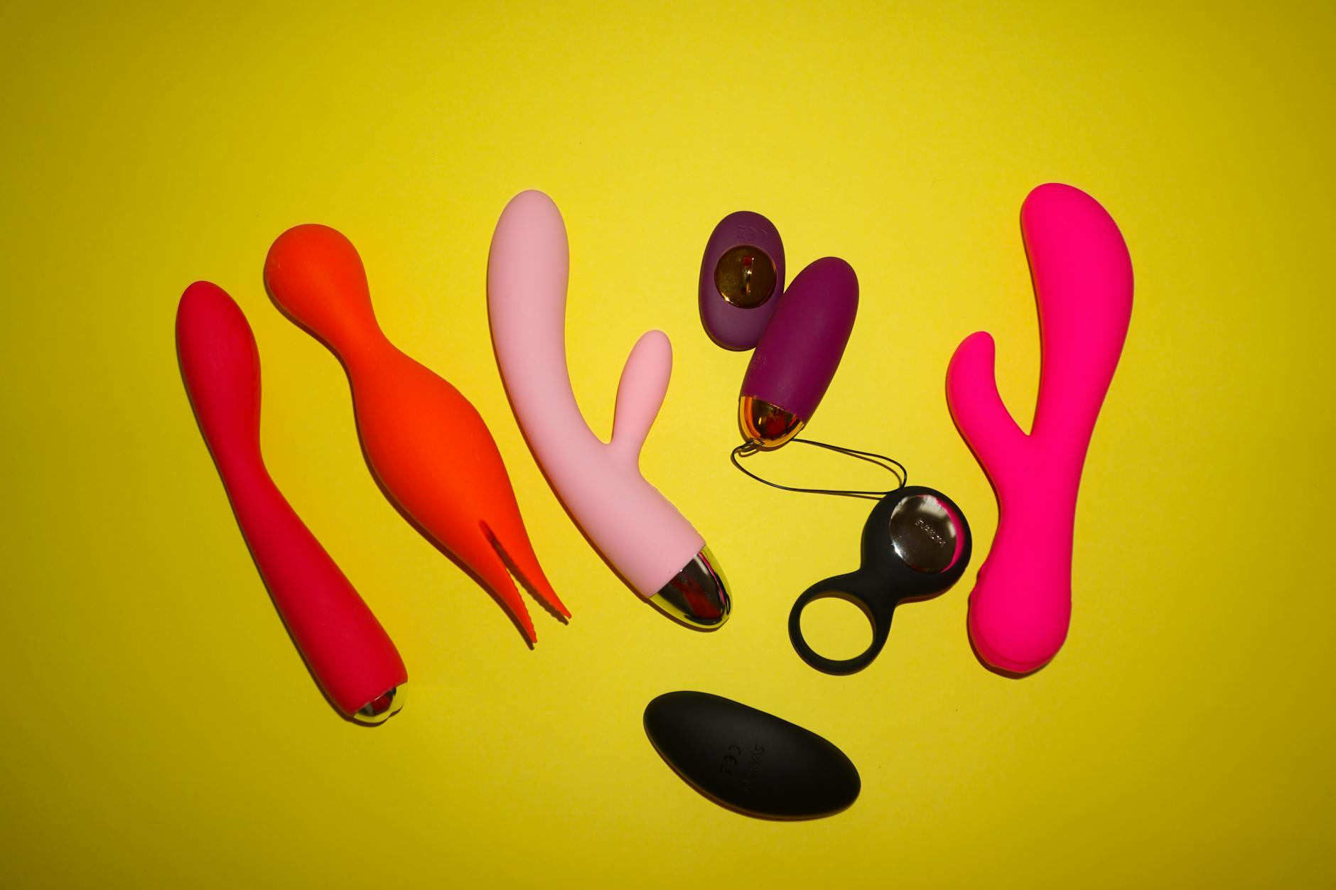 Close-up of a hand holding an orange vibrator against a minimalistic purple backdrop