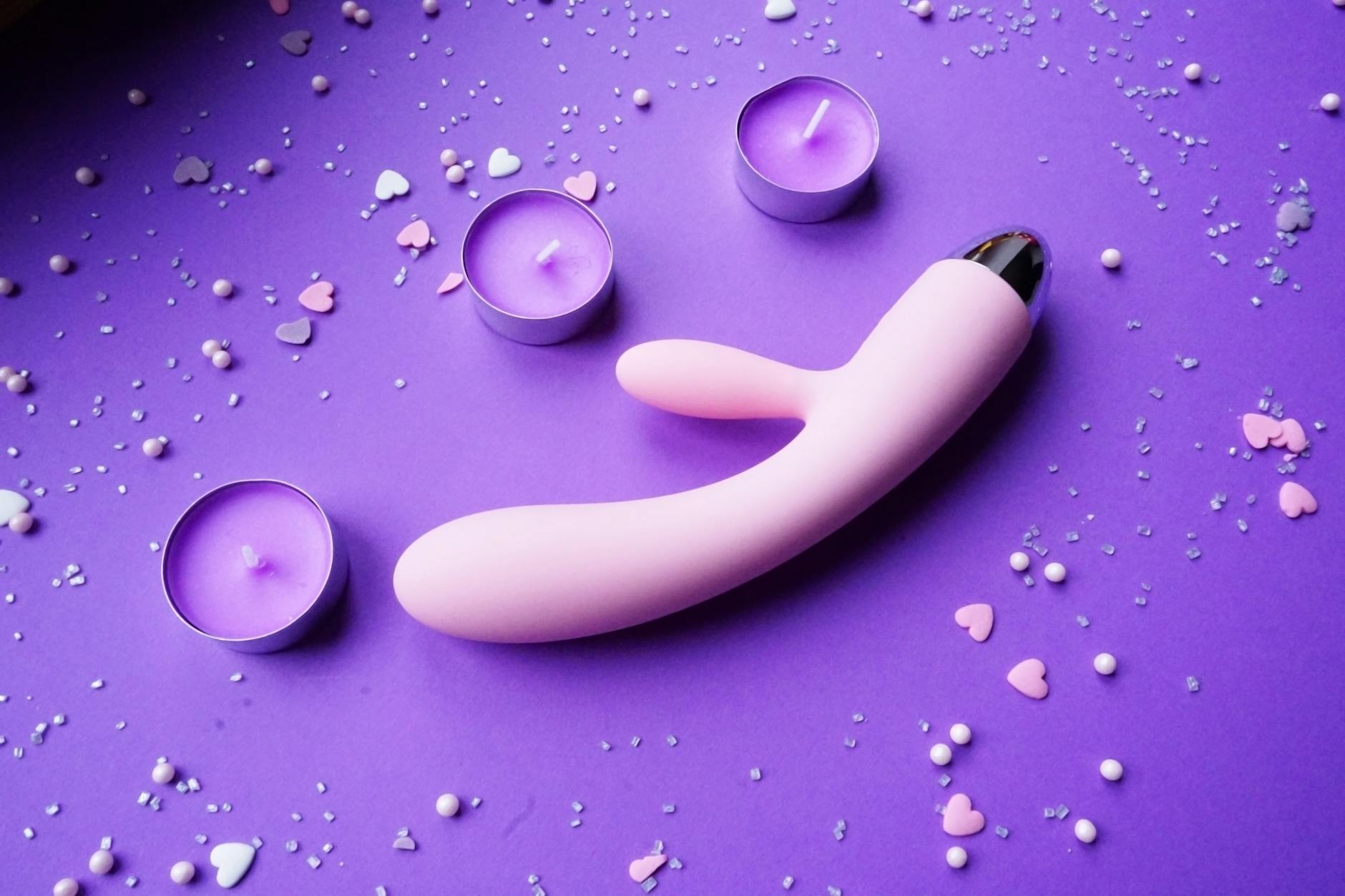 Lemon vibrator on purple background with romantic candlelight and heart confetti